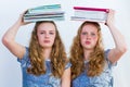 Two schoolgirls with textbooks on their heads