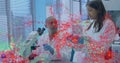 Two scientists examining samples under microscope in lab, wearing labcoats with digital overlay Royalty Free Stock Photo