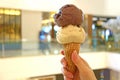 Two scoops of peanut butter and chocolate ice cream cone in woman`s hand