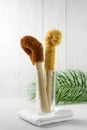 Two scrapers made of coconut bristles and a bamboo handle in a glass cup on a light background. Royalty Free Stock Photo