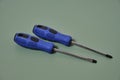 Two screwdrivers cross and flat with blue handles on a green background Royalty Free Stock Photo