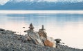 Two sculptures of balancing rocks on a lake shore