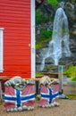 Two sculptures of trolls with norwegian flags and Steinsdalsfossen waterfall in the background, Norway