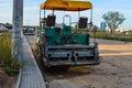 Two-seater asphalt paving machine, open car with awning and yellow fabric roof. the asphalt paving bucket is installed at the rear Royalty Free Stock Photo