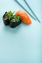 Two seaweed Sushi Chuka and sushi nigiri with salmon with chopsticks on a blue background