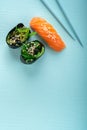 Two seaweed Sushi Chuka and sushi nigiri with salmon with chopsticks on a blue