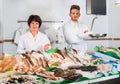 Two sellers posing near display with frozen fish Royalty Free Stock Photo