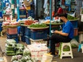 Two persons at an outdoor street market in Bangkok, Thailand, are waiting for customers to sell ther red and green chili fruits