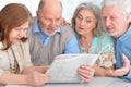 Two senior couples sitting at table and reading newspaper Royalty Free Stock Photo