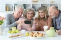 Two senior couples using smartphone during morning tea