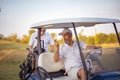 Two senior men golfers on court. Man sitting in golf cart.  Two senior men golfers on court Royalty Free Stock Photo