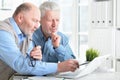 Two senior men sitting at table and using laptop Royalty Free Stock Photo