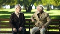 Two senior people laughing remembering young years sitting on bench in park Royalty Free Stock Photo