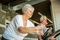 Two senior people working out on elliptical machine. Senior woman using smart phone. Royalty Free Stock Photo