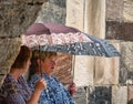 Two senior women holding umbrellas and talking