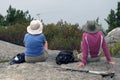 Two senior women sitting on rock face at top of a mountain