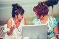 Two senior women talking and using laptop on a laptop in outdoor cafe Royalty Free Stock Photo