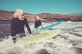 Two seniors going surf together with wetsuits and surfboards entering in the water to take a waves or learn how to take - summer