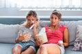 Two sentimental women friends upset crying and wiping tears with handkerchiefs while watching dramatic, sad movie, TV reality show Royalty Free Stock Photo