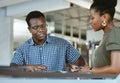 Two serious african american businesspeople having a meeting together at work. Businessman and businesswoman talking in Royalty Free Stock Photo