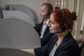 Two serious call center employees are talking with clients. Man and woman working with headsets in office. Royalty Free Stock Photo