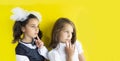 Two serious and dreamy schoolgirls. cute caucasian girls with brown and blond hair on yellow background. The concept