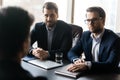 Two serious HR businessmen listening male applicant during work interview. Royalty Free Stock Photo