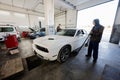 Two service man mechanics in repair station working with muscle car. Man worker jacks up the car to diagnose the chassis