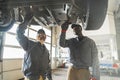 two servicemen working on a car using special tools, medium shot car workshop Royalty Free Stock Photo