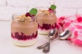 Two servings of chocolate-vanilla pudding with berries and a jar on a white background.