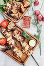 Two servings of delicious charcoal shashlik. Fried meat on a wooden plate. Grilled meat on skewers, baked vegetables and sauce.