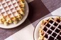 Two servings of fresh homemade Belgian waffles on a checkered tablecloth