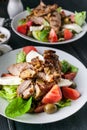 Two servings of grilled meat and salad with vegetables, mozzarella and herbs. Traditional Mediterranean Cuisine. Vertical shot