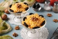 Two servings of salad with chicken, cheese and apples, decorated prunes and walnuts in glass bowls on light blue background,