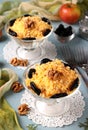 Two servings of salad with chicken, cheese and apples, decorated prunes and walnuts in glasses bowls on light blue