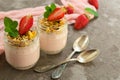 Two servings of strawberry yogurt with granola and fresh strawberries on a gray background. Close-up.