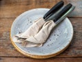 Two set of clean fork and knife wrapped in tissue napkin in the ceramic dish Royalty Free Stock Photo