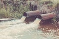 two sewer pipes pour out to the river/Industrial Pipe Dumping Waste Water Into The river. Toned Royalty Free Stock Photo