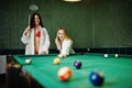 Two sexy girls in white bathrobe and swimsuit play pool billiards Royalty Free Stock Photo