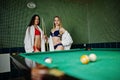 Two sexy girls in white bathrobe and swimsuit play pool billiards Royalty Free Stock Photo