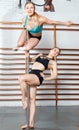 Two sexy young women exercising pole dance moves together on one pylon in gym Royalty Free Stock Photo
