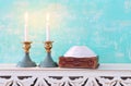 Two shabbat candlesticks with burning candles over wooden table