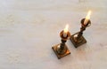 Two shabbat candlesticks with burning candles over wooden table. top view