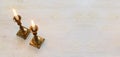 two shabbat candlesticks with burning candles over wooden table. top view. low key