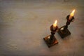 two shabbat candlesticks with burning candles over wooden table. top view. low key