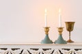 Two shabbat candlesticks with burning candles over wooden table