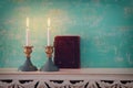 Two shabbat candlesticks with burning candles over wooden table