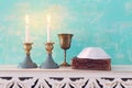 Two shabbat candlesticks with burning candles over wooden table