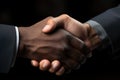 Two sharp dressed businessmen shake hands against a cool black backdrop, formal business meeting image