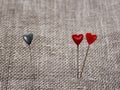 Two sharp pins in the form of red hearts near and one blue stuck Royalty Free Stock Photo